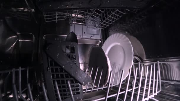 Чоловік відкриває двері посудомийної машини і витягує кошик посуду
 - Кадри, відео
