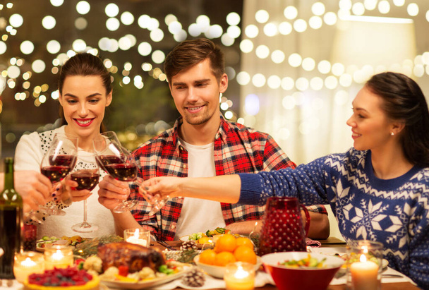 happy friends drinking red wine at christmas party - Foto, Imagen