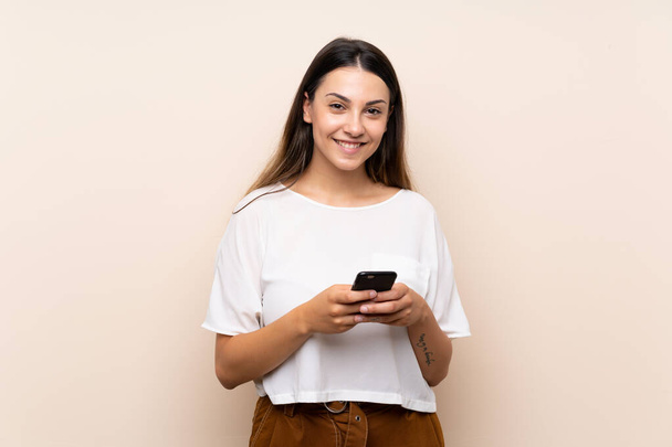 Young brunette woman over isolated background sending a message with the mobile - Photo, Image