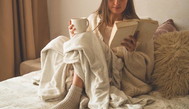 Sıcak bir sonbahar kış akşamı. Sıcak çay içip kitap okuyan bir kadın..  - Fotoğraf, Görsel