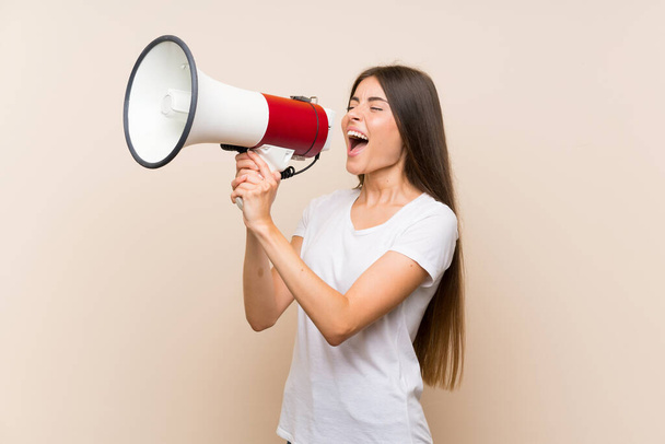Pretty young girl over isolated background shouting through a megaphone - Foto, Imagen