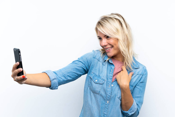 Nuori blondi nainen yli eristetty valkoinen tausta tekee selfie
 - Valokuva, kuva