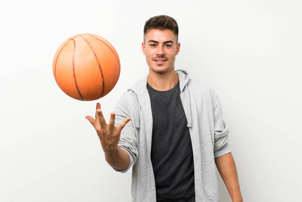 Άθλημα άνθρωπος πάνω από απομονωμένο λευκό τοίχο με μπάλα του μπάσκετ - Φωτογραφία, εικόνα