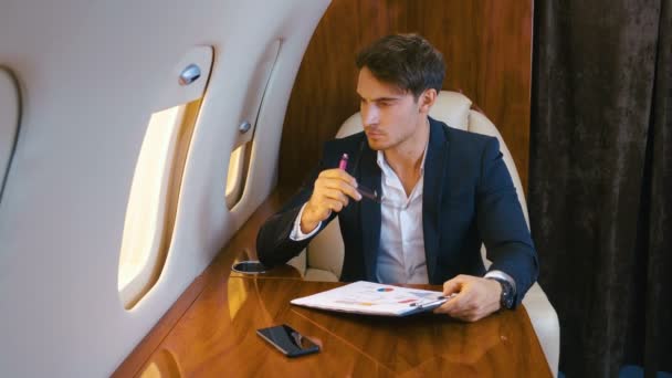 Businessman works with documents while flying in a personal jet plane. Business Class. - Footage, Video