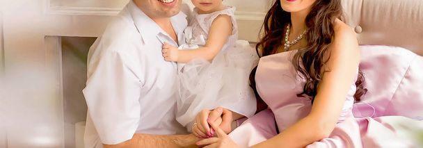 dad holds  his little princess daughter wiht mam on the sofa - Φωτογραφία, εικόνα