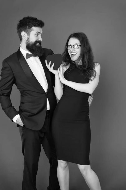 Couple in love dating anniversary. Man tuxedo and girl hold hear soft toy romantic anniversary. Valentines day holiday. Do not play with my heart. Man with beard and woman happy celebrate anniversary - Foto, imagen