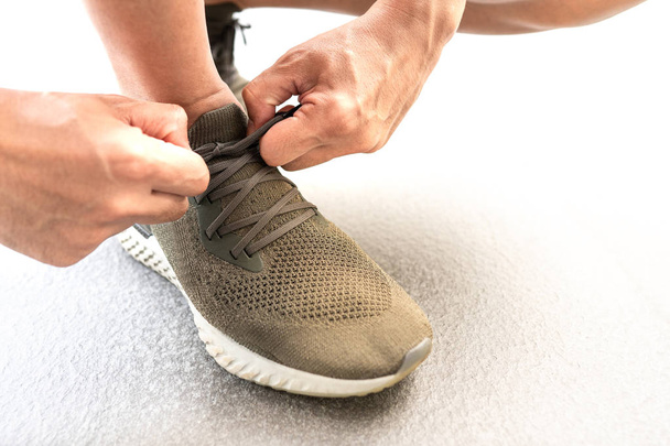 Мужские руки завязывают шнурки на кроссовках перед тренировкой. Бегун готовится к тренировке. Концепция активного образа жизни спортсмена
. - Фото, изображение