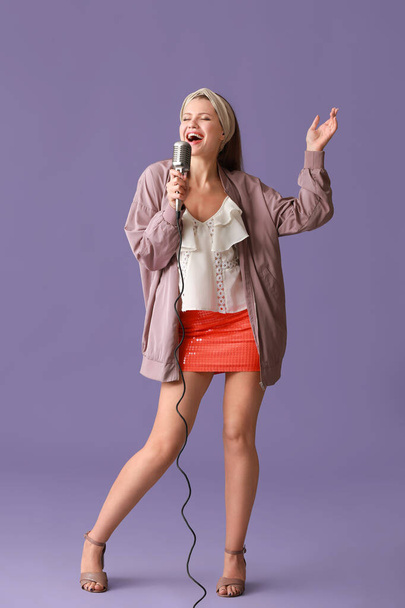 Beautiful young female singer with microphone on color background - Zdjęcie, obraz