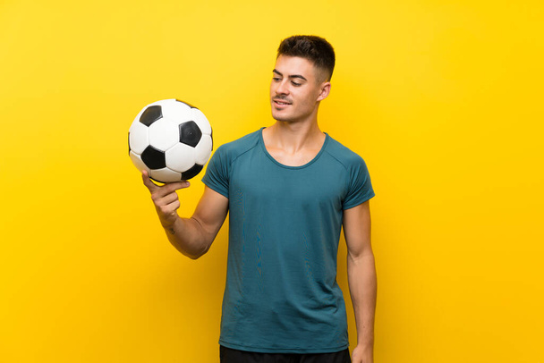Guapo joven jugador de fútbol hombre sobre aislado fondo amarillo con expresión feliz
 - Foto, imagen