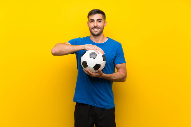 Joven jugador de fútbol guapo hombre sobre aislado pared amarilla
 - Foto, imagen
