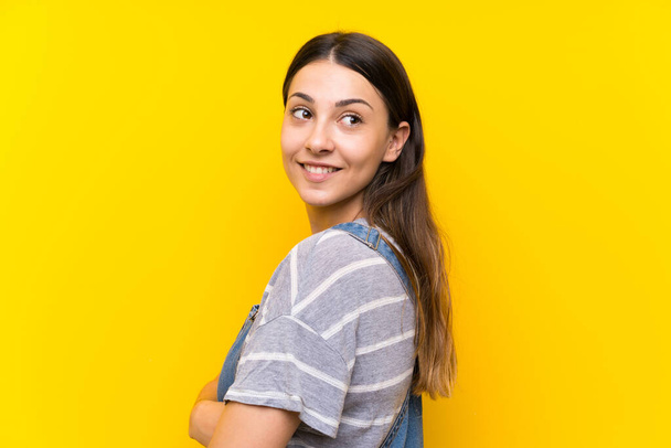 jovem mulher no dungarees sobre isolado amarelo fundo rindo
 - Foto, Imagem