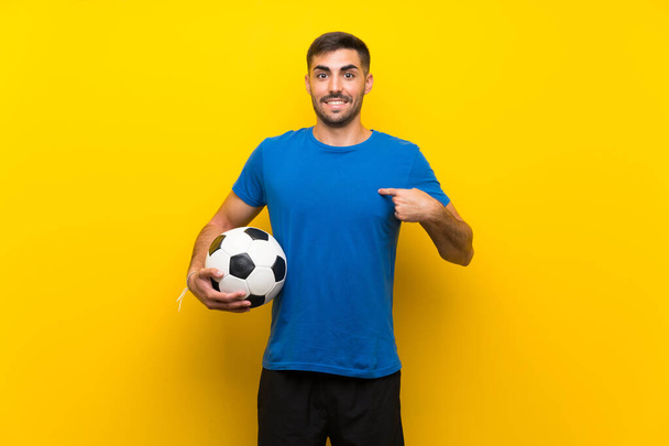 Giovane bel giocatore di calcio uomo oltre isolato muro giallo con espressione facciale sorpresa
 - Foto, immagini