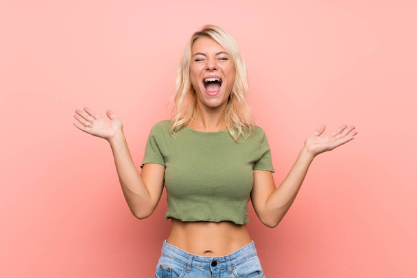 junge blonde Frau über isoliertem rosa Hintergrund lächelt viel - Foto, Bild