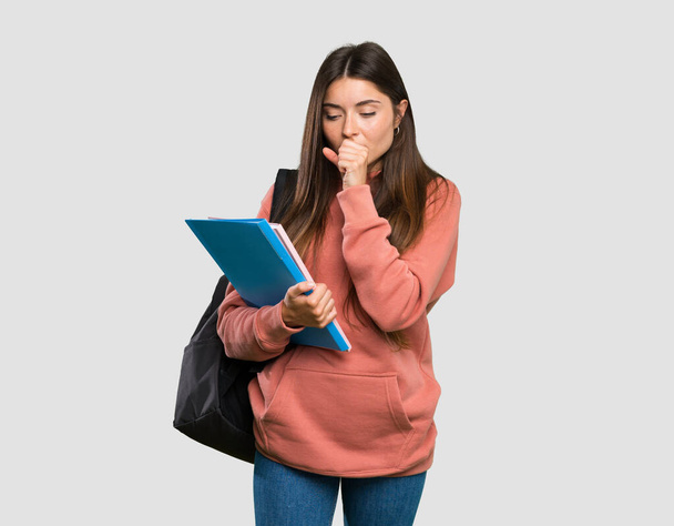 Young student woman holding notebooks is suffering with cough and feeling bad over isolated grey background - Photo, Image