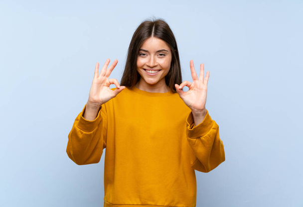 Caucasian young woman over isolated blue wall showing an ok sign with fingers - Foto, Bild