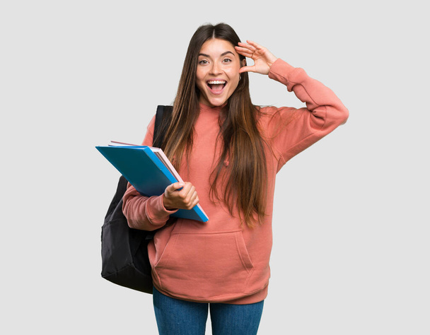 Jeune étudiante tenant des carnets avec expression surprise sur fond gris isolé
 - Photo, image