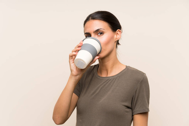 Jonge vrouw die een take-away koffie vasthoudt - Foto, afbeelding