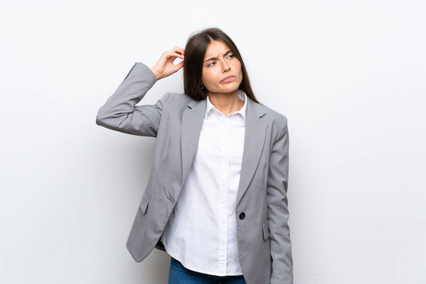 Young business woman over isolated white background having doubts while scratching head - Foto, Imagem