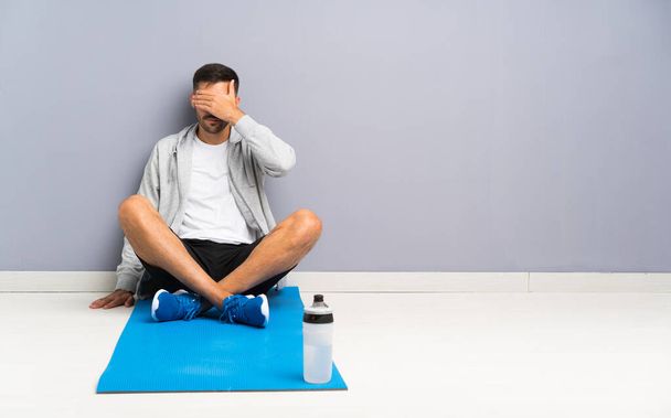 Sport man sitting one the floor covering eyes by hands - Photo, Image