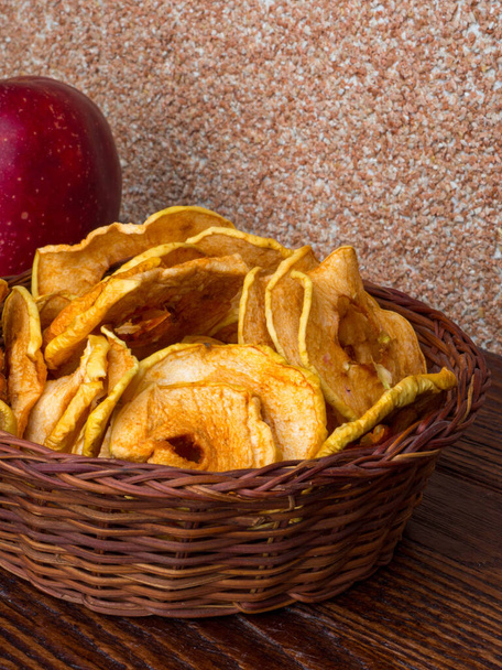 Homemade sun-dried organic apple slices, crispy apple chips, on wooden background and fresh apple. - Foto, Imagen