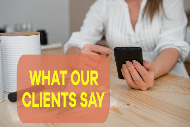Writing note showing What Our Clients Say. Business photo showcasing testimonials or feedback of aclient about the product woman using smartphone and technological devices inside the home. - Photo, Image