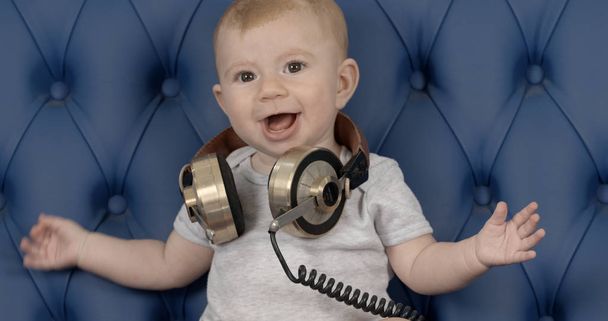 adorable bébé dj avec de grands écouteurs vintage sur canapé en cuir bleu
 - Photo, image