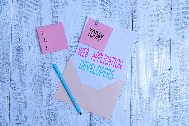 Conceptual hand writing showing Web Application Developers. Business photo text Internet programming experts Technology software Envelope blank sheet sticky note ballpoint wooden background. - Photo, Image
