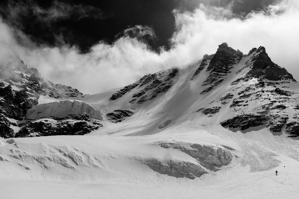 Ο άνθρωπος κατεβαίνει τον παγετώνα Γκραν Παραντίσο το χειμώνα στη βορειοδυτική πλευρά. Το peack είναι το ψηλότερο βουνό εξ ολοκλήρου στην ιταλική επικράτεια. - Φωτογραφία, εικόνα