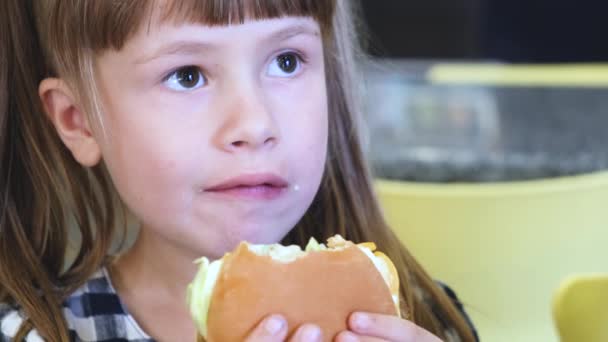 Mooi kind meisje eten Fast Food in restaurant. - Video