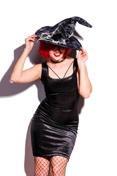 Menina com cabelo ruivo em um chapéu de bruxa isolado em branco. Conceito de Halloween
. - Foto, Imagem