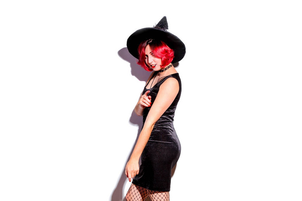 Chica con el pelo rojo en un sombrero de bruja aislado en blanco. Concepto Halloween
. - Foto, imagen
