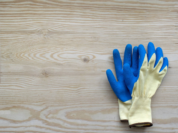 Blue protective rubber gloves for construction and operation with caustic substances on a bright wooden background. Rubber gloves for repair. - 写真・画像