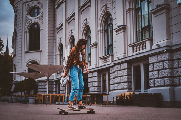 Womam is riding longboard on the street - Photo, Image