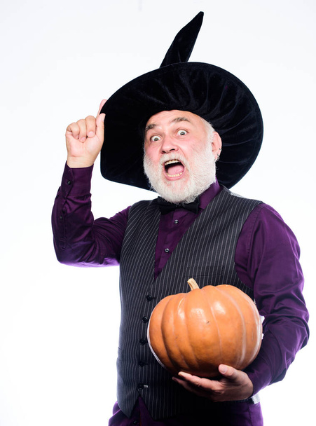 Halloween is a real treat. Stargazer in holiday costume. Traditional food. evil wizard hold orange pumpkin. happy halloween. bearded man ready for halloween party. mature man magician in witch hat - Φωτογραφία, εικόνα