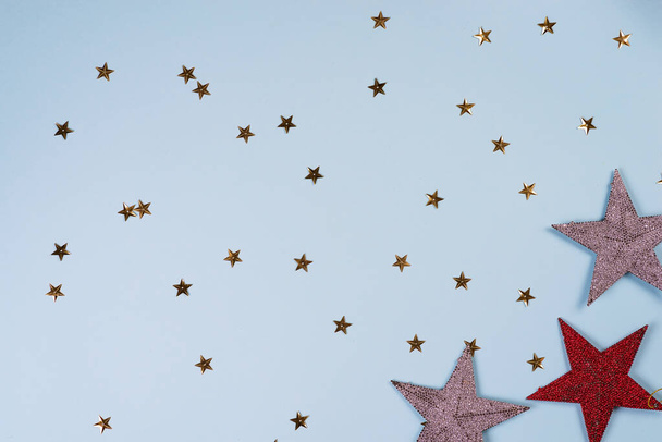 Christmas pattern made of golden, silver and red stars on blue background. Winter concept. Flat lay. - Foto, afbeelding