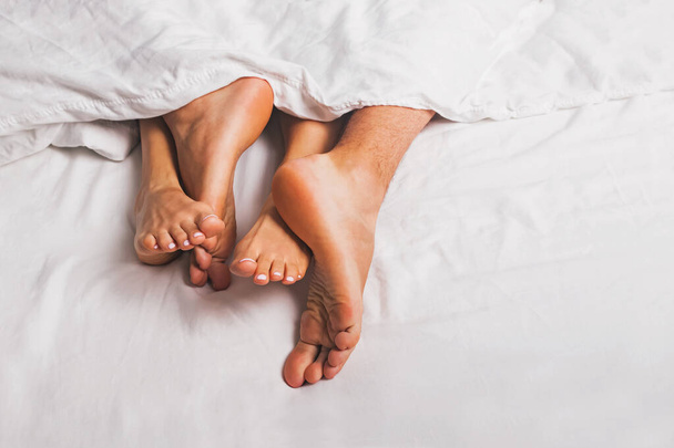 Feet of man and woman having sex in a bed - Фото, зображення