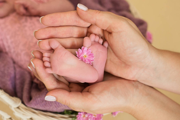  Vastasyntyneen tytön jalat vaaleanpunaisilla kukilla, sormilla jalka, äidin hoito, rakkaus ja perheen halaukset, arkuus.
.  - Valokuva, kuva