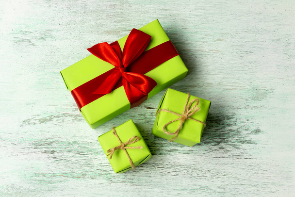 Green gift boxes tied with a blue ribbon and twine on a light wooden background, top view - Foto, immagini