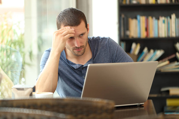 Беспокойный взрослый мужчина проверяет содержимое ноутбука в кофейне
 - Фото, изображение