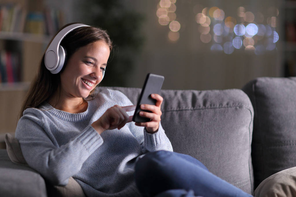Happy woman listening to music using phone in the night - Foto, afbeelding