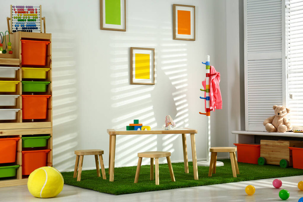 Stylish playroom interior with wooden table and stools - Фото, зображення