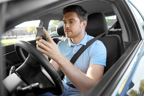 man driving car and using smartphone - Foto, afbeelding