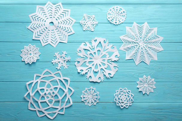 Flat lay composition with paper snowflakes on blue wooden background. Winter season - Fotó, kép