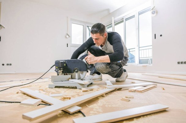 male worker installing oak parquet floor during home improvement   - Foto, afbeelding