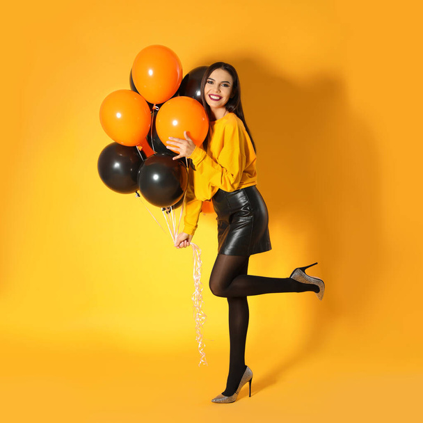 Beautiful woman with balloons on yellow background. Halloween party - 写真・画像
