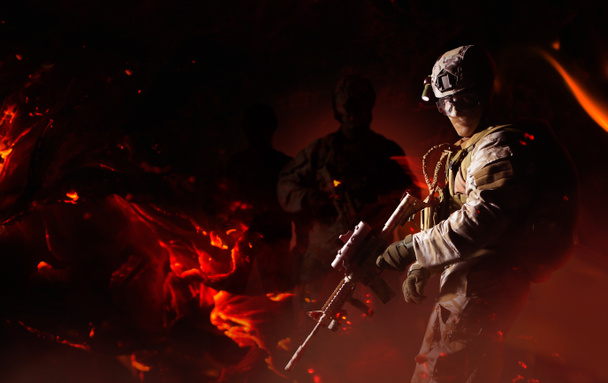 Полностью оборудованный солдат пустыни, стоящий с винтовкой на заднем плане огня
 - Фото, изображение