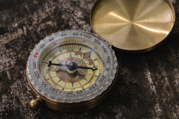 Golden vintage compass on wooden background with natural light - Foto, afbeelding
