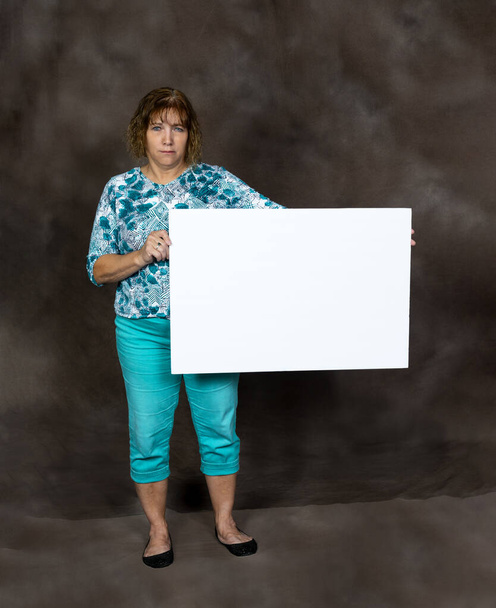 Mérges vagy aggódó középkorú nő, aki üres jelet tart - Fotó, kép