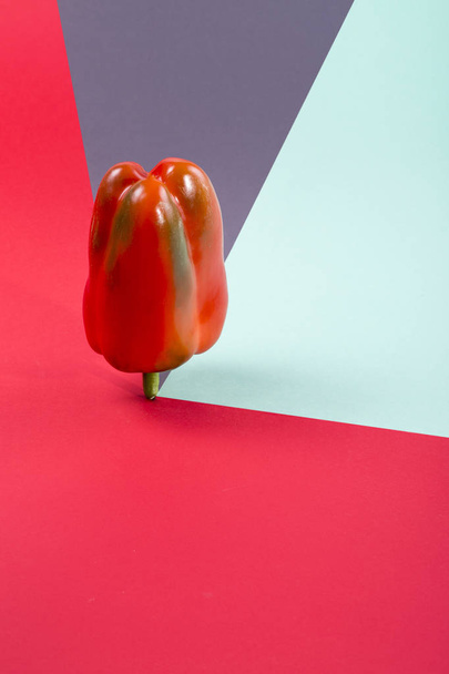 Abstrakti asetelma punaisella paprikalla värillisellä taustalla
 - Valokuva, kuva