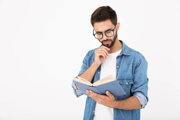 Image of serious smart man wearing eyeglasses holding and reading book - Fotoğraf, Görsel